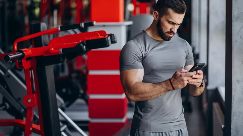 application de musculation gratuite affichée sur smartphone dans une salle de sport