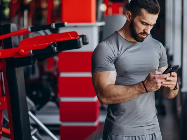 application de musculation gratuite affichée sur smartphone dans une salle de sport