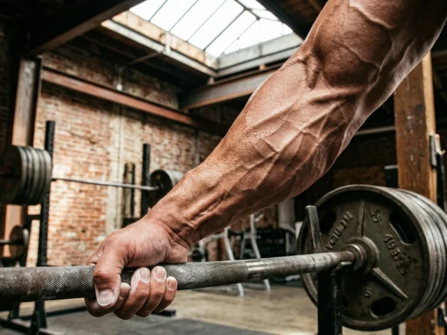 Pratiquant musclant ses avant-bras en serrant une barre, avant-bras contracte